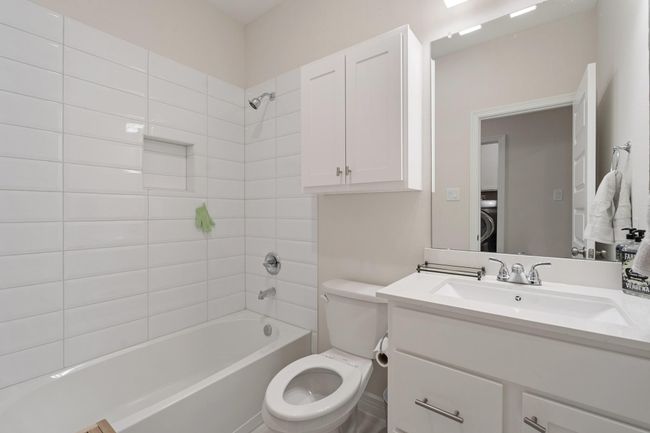 Spacious full bathroom with tile flooring and tile surround. | Image 22