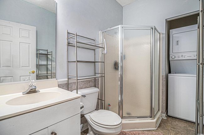 Full bathroom featuring stacked washer and dryer, a shower stall, and vanity | Image 11