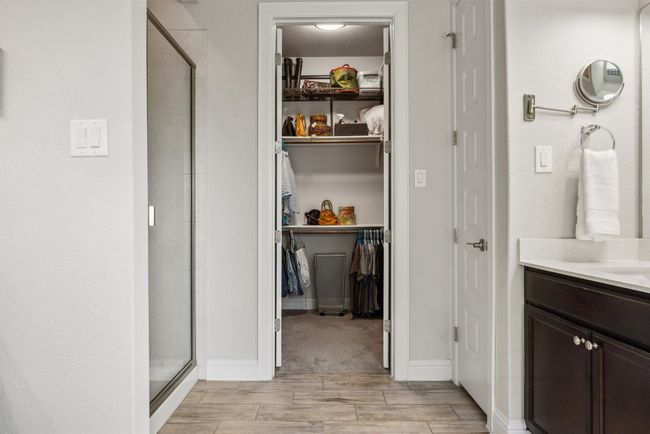 Bathroom with a stall shower, a walk in closet, vanity, and wood finished floors | Image 24