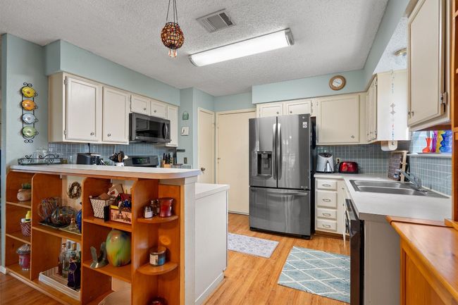 The kitchen with stainless steel appliances is tucked away, but still open to the living area. | Image 12