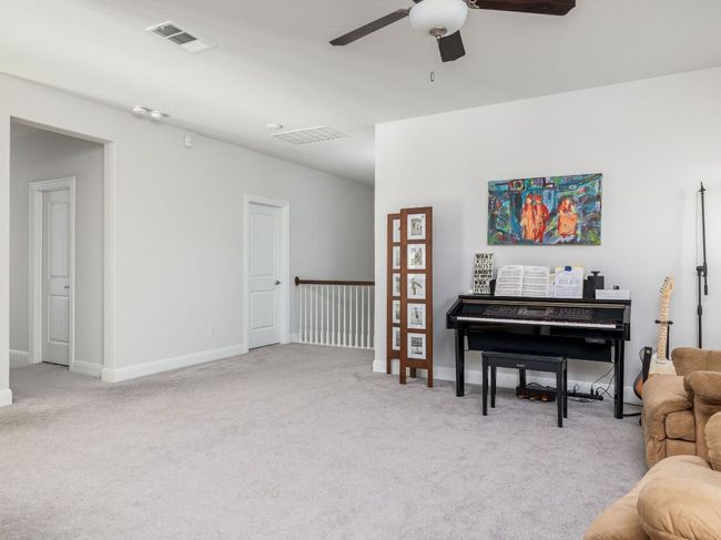 Living area featuring a ceiling fan, baseboards, light colored carpet, and visible vents | Image 19