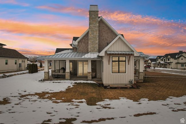 Snow covered house with metal roof, a porch, board and batten siding, a standing seam roof, and a chimney | Image 69