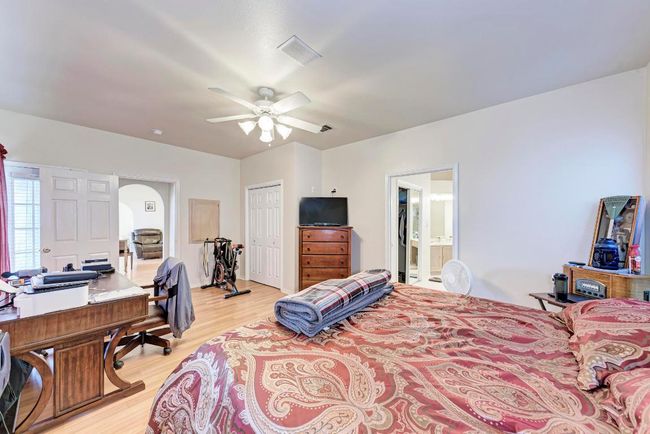 Bedroom featuring light wood-type flooring, a desk, arched walkways, a closet, and a ceiling fan | Image 24