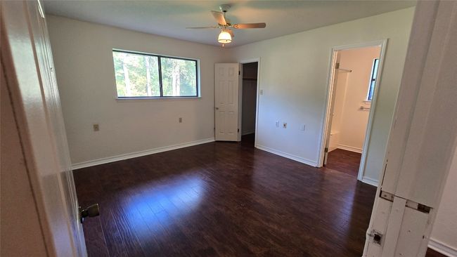 Unfurnished bedroom featuring dark wood-type flooring, ensuite bathroom, and ceiling fan | Image 15