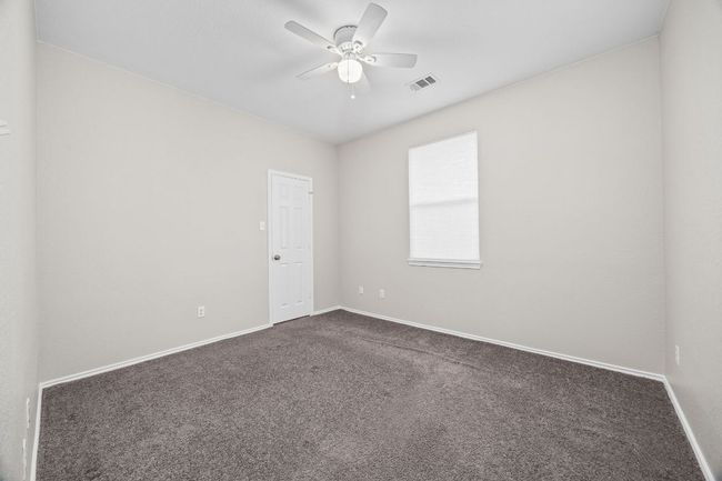 Unfurnished room featuring dark colored carpet, visible vents, a ceiling fan, and baseboards | Image 27