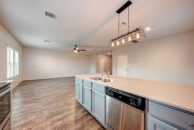 Kitchen with appliances with stainless steel finishes, a sink, a ceiling fan, hanging light fixtures, and open floor plan | Image 14