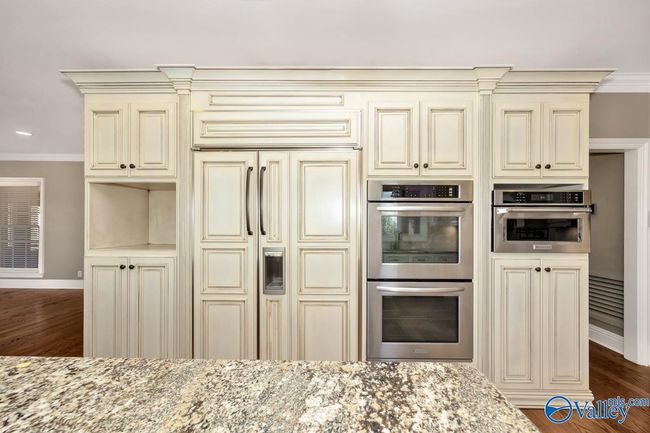 Wood flooring, wood cabinetry, kitchen island with bar seating, recessed lighting | Image 19