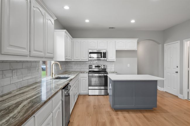 Kitchen with appliances with stainless steel finishes, a sink, white cabinetry, light wood-style floors, and recessed lighting | Image 7