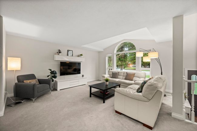 Living room with light colored carpet, baseboards, and lofted ceiling | Image 8