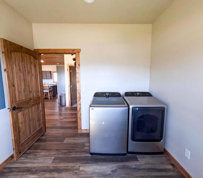 Laundry area featuring dark wood finished floors, baseboards, and washer and dryer | Image 18