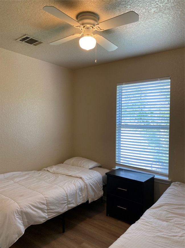 Bedroom featuring wood finished floors, a textured ceiling, and a ceiling fan | Image 9