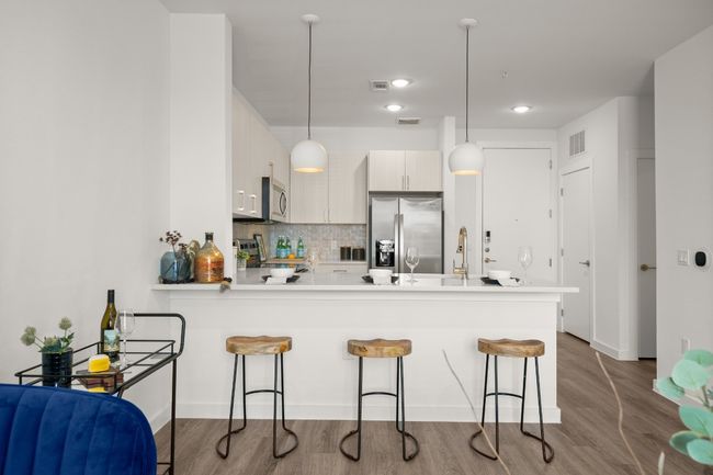Kitchen featuring appliances with stainless steel finishes, a breakfast bar, a peninsula, decorative light fixtures, and quartz countertops *Photos are of similar unit* | Image 8