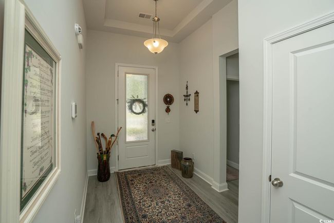 Foyer entrance with wood finished floors, a raised ceiling, and baseboards | Image 11