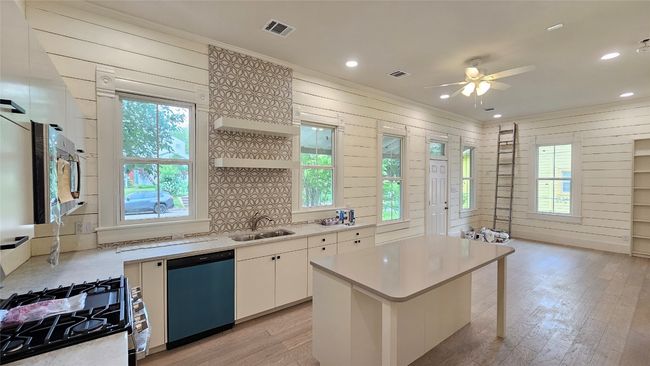 Kitchen with appliances with stainless steel finishes, a sink, light countertops, light wood-type flooring, and a ceiling fan | Image 4