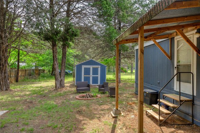 View of yard featuring an outbuilding, fence, a storage unit, and entry steps | Image 7