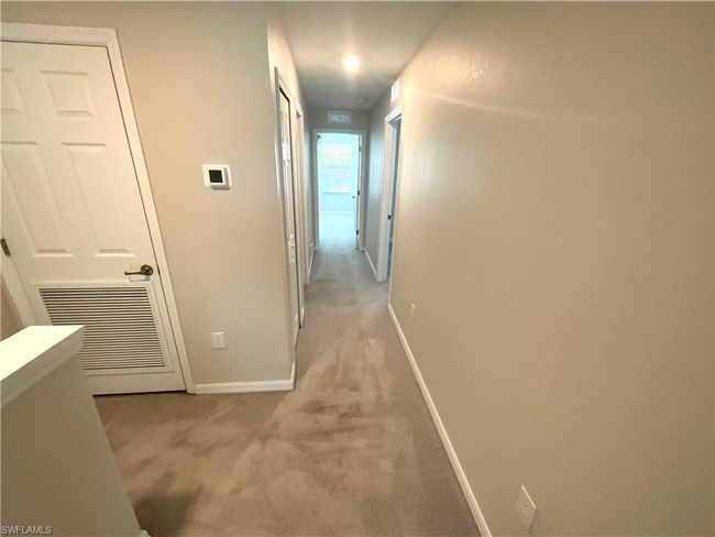 Hallway with light carpet and baseboards | Image 16