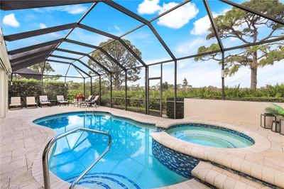 View of swimming pool with an in ground hot tub, a patio area, and glass enclosure | Image 1