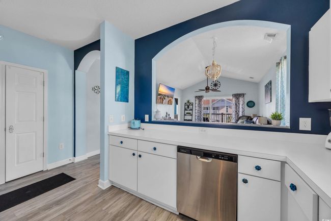 Kitchen featuring light countertops, arched walkways, light wood-style floors, white cabinetry, and dishwasher | Image 10