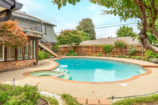 View of swimming pool with a fenced backyard, a pool with connected hot tub, and stairs | Image 37