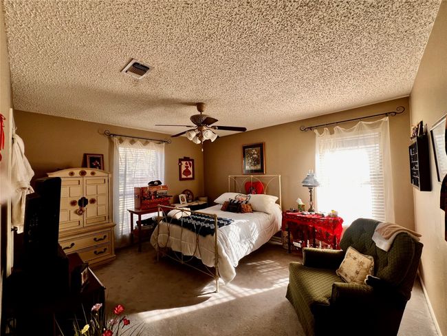 Carpeted bedroom featuring multiple windows, ceiling fan, and a textured ceiling | Image 9