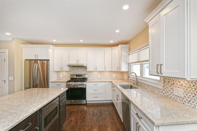 Kitchen featuring white cabinets, under cabinet range hood, stainless steel appliances, and a sink | Image 15
