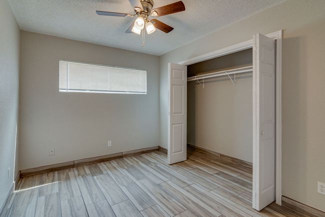 Unfurnished bedroom with a closet, a ceiling fan, a textured ceiling, and light wood-type flooring | Image 15
