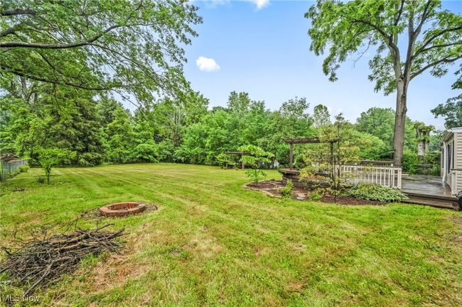 View of green lawn featuring an outdoor fire pit and a deck | Image 42