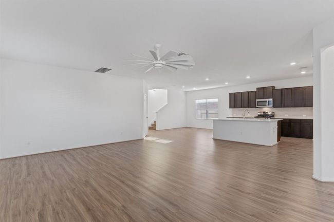 Unfurnished living room featuring light wood-style flooring, stairs, a ceiling fan, and recessed lighting | Image 11
