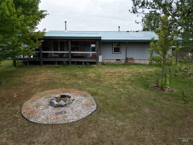 Rear view of house featuring crawl space, a yard, an outdoor fire pit, and a metal roof | Image 24