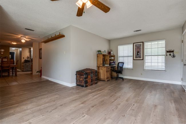 Living room with a textured ceiling, a ceiling fan, baseboards, wood finished floors, and visible vents | Image 14