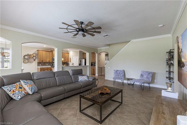 Living room with visible vents, baseboards, ceiling fan, ornamental molding, and a textured ceiling | Image 5