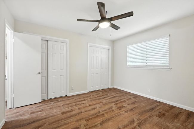 Unfurnished bedroom featuring multiple closets, wood finished floors, and ceiling fan | Image 12