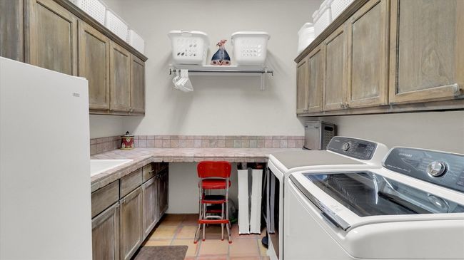 Washroom featuring washer and dryer, cabinet space, and light tile patterned floors | Image 20