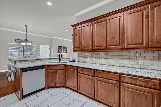 Kitchen featuring a sink, brown cabinetry, dishwasher, and an inviting chandelier | Image 15