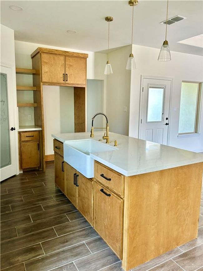 Kitchen with open shelves, hanging light fixtures, a sink, visible vents, and wood tiled floor | Image 7