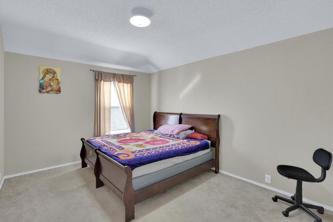 Bedroom with light colored carpet, a textured ceiling, and baseboards | Image 29