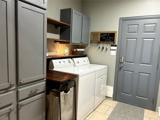 Extra big laundry room with built in cabinets light tile flooring. The large panty is opposite the washer & dryer. | Image 14