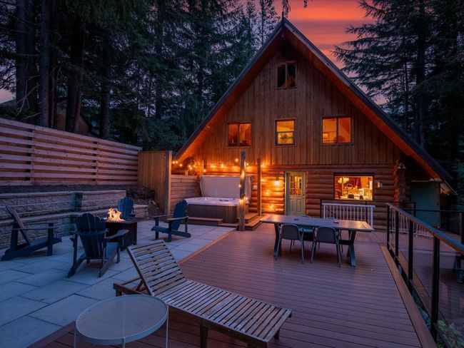 Exterior space featuring an outdoor fire pit, a hot tub, a fenced backyard, and outdoor dining space | Image 32