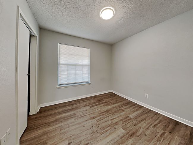 Unfurnished bedroom with wood finished floors, a closet, and a textured ceiling | Image 11