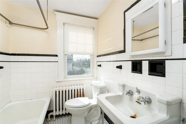 Bathroom featuring a tub to relax in, radiator heating unit, a wainscoted wall, toilet, and tile walls | Image 14