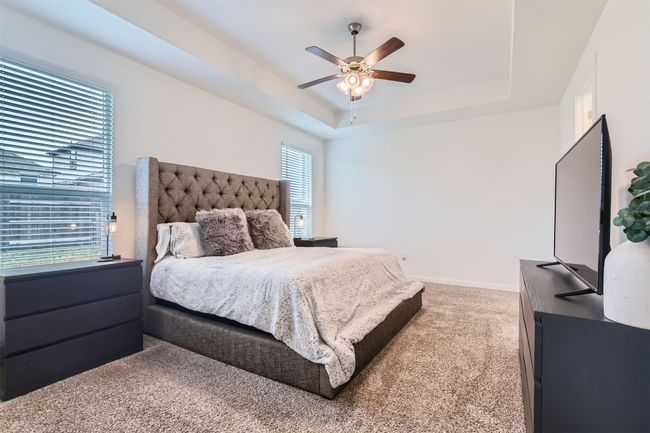Carpeted bedroom featuring a raised ceiling, a ceiling fan, and baseboards | Image 14