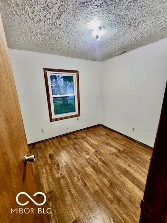 empty room with wood finished floors, a textured ceiling, and baseboards | Image 7