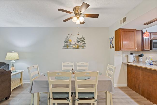 Dining space with light wood-style floors, a textured ceiling, a ceiling fan, baseboards, and visible vents | Image 11