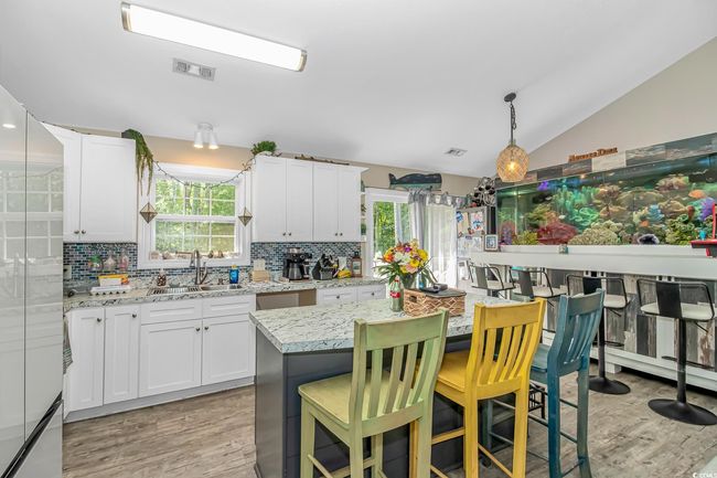 Kitchen with a sink, light wood finished floors, lofted ceiling, tasteful backsplash, and plenty of natural light | Image 8