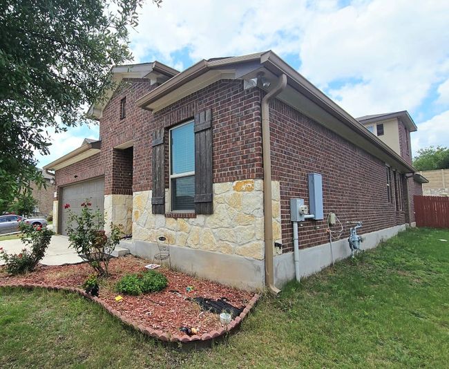 View of side of property featuring an attached garage, brick siding, stone siding, and concrete driveway | Image 24