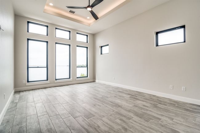 Spare room featuring a healthy amount of sunlight, light hardwood / wood-style floors, ceiling fan, and a raised ceiling | Image 11