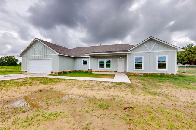 Ranch-style house featuring roof with shingles, board and batten siding, a garage, and concrete driveway | Image 12