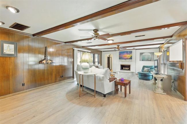 The spacious den has paneled walls, luxury vinyl plank floors, two ceiling fans and a one of kind Cordova Shell Stone fireplace designed and crafted by the seller. | Image 10