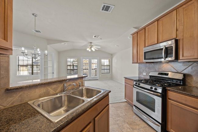 Kitchen featuring vaulted ceiling, visible vents, stainless steel appliances, and a sink | Image 16
