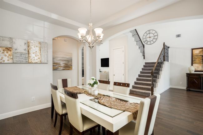 Dining room featuring stairway, a chandelier, arched walkways, dark wood finished floors, and baseboards | Image 6